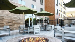 An outdoor seating area with a fire pit, umbrellas, and modern furniture. - Fairfield Inn & Suites by Marriott Ontario Rancho Cucamonga (Rancho Cucamonga)