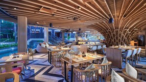 A modern restaurant with a curved ceiling, wooden furniture, and a view of the outdoors.