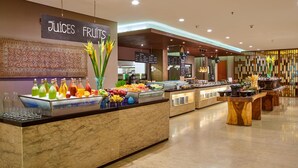 A buffet area with a sign reading "JUICES FRUITS" and a variety of fruits and beverages.
