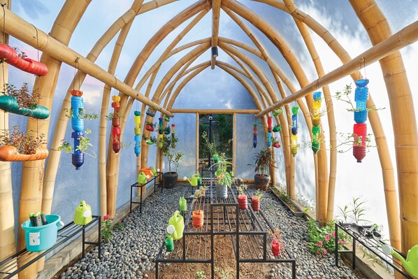 A greenhouse with a bamboo arch structure, potted plants on shelves, and a gravel floor. - Marriott’s Bali Nusa Dua Gardens (Nusa Dua)