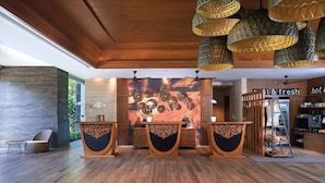 A reception area with wooden flooring, a central counter with intricate carvings, and a wall with a circular design.