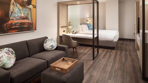 A modern hotel room with a sofa, a desk, a bed, and a large mirror. - SpringHill Suites by Marriott New Orleans Downtown/Canal Street (New Orleans)