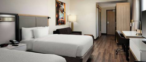 A hotel room with two beds, a desk, a chair, a lamp, and a painting on the wall.