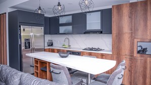 Eine moderne Küche mit Kochinsel, Edelstahlgeräten und Holzschränken.