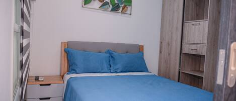 A bedroom with a bed, a nightstand, a wardrobe, and a wall art piece.