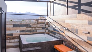 Ein modernes Badezimmer mit einer großzügigen Badewanne, einer Sitzbank und Blick auf Berge.