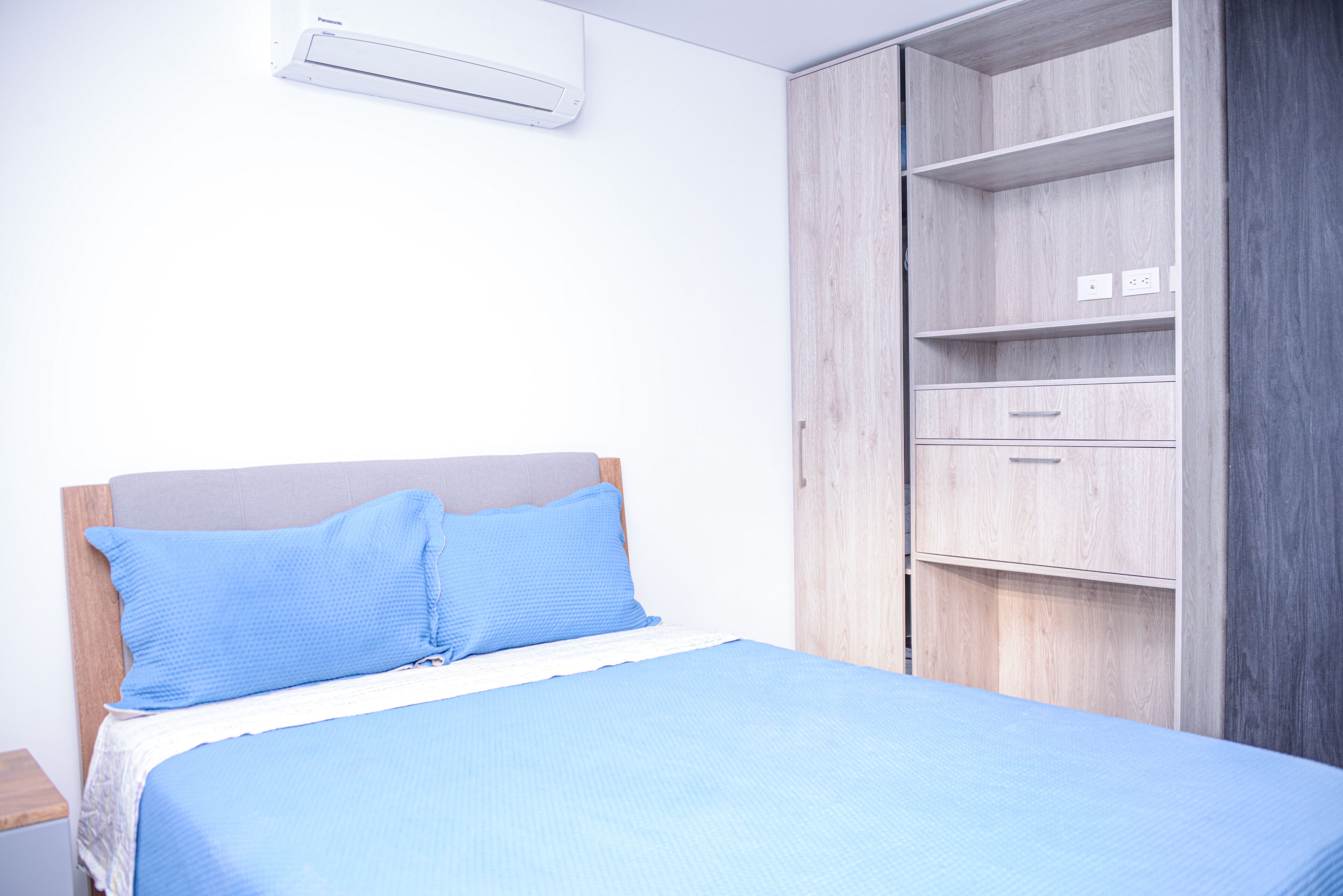 A bedroom with a bed, a wardrobe, and a nightstand.