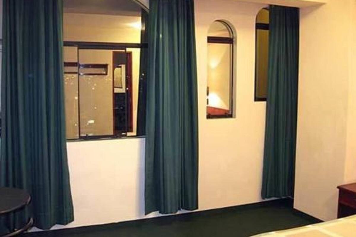 A hotel room with a bed, a desk, a chair, and a large mirror.