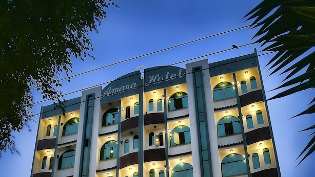 Un hotel a più piani con ingresso centrale, balconi e insegna che indica che si tratta di un albergo.