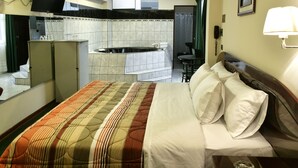 Una camera d'albergo con un letto, un tavolino, una sedia, una scrivania, un telefono, una televisione e un bagno dotato di vasca e servizi igienici.