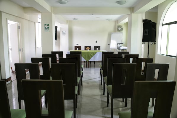 A conference room with a long table, chairs, a whiteboard, and a projector.
