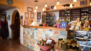 A bar area with a stone counter, hanging lights, and a variety of bottles and jars.