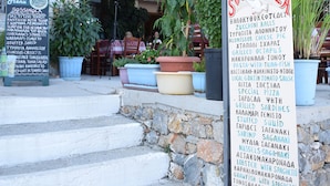 A restaurant with a stone facade, outdoor seating, and a menu board listing various dishes.
