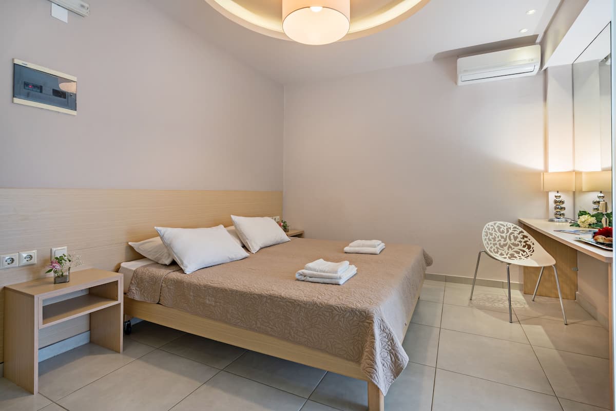 Una habitación de hotel moderna con cama, mesita de noche, silla, escritorio y espejo.