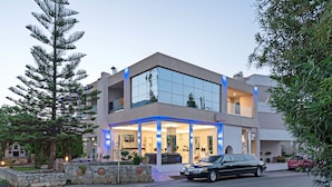 Una casa moderna de dos pisos con fachada de vidrio, un área exterior techada y un muro de piedra.