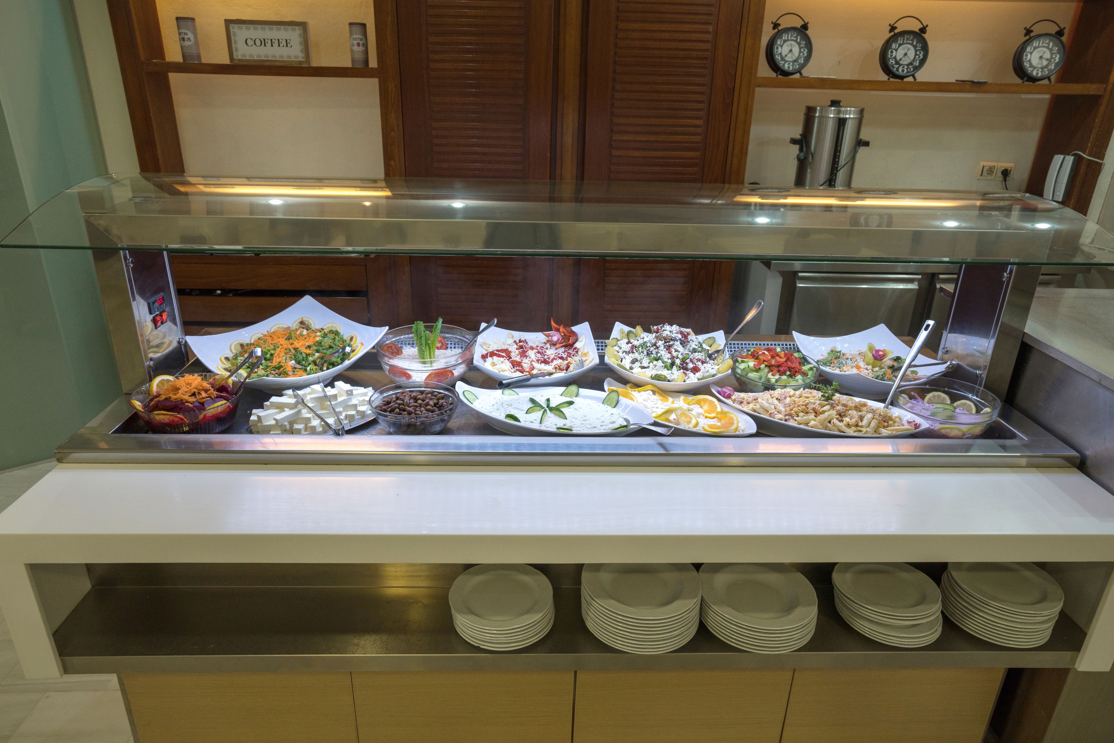 A buffet with various dishes, a coffee station, and a clock on the wall.