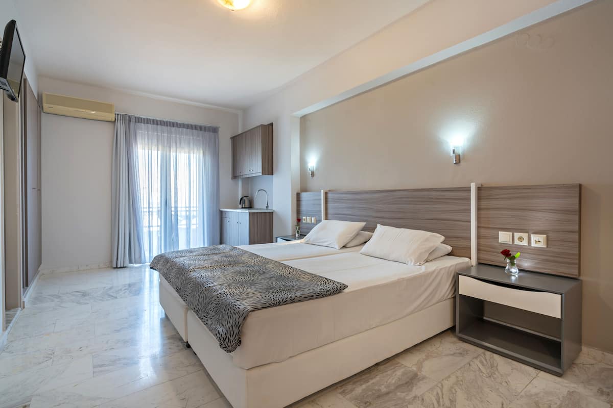 Una habitación de hotel moderna con una cama grande, mesitas de noche, un armario y un baño con ducha e inodoro.