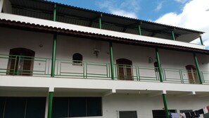 A two-story building with a flat roof, green railings, and multiple windows.