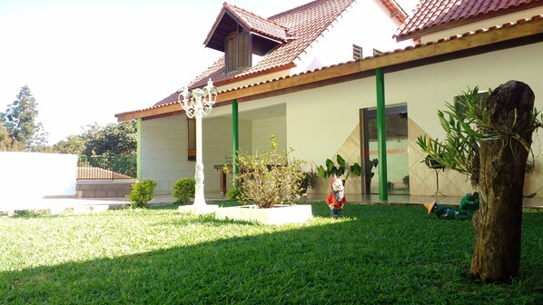 A building with a tiled roof, a covered entrance, and a well-maintained lawn.