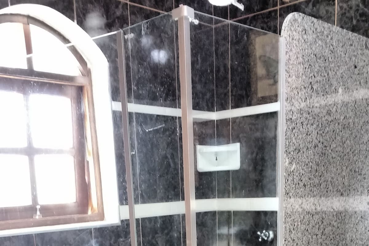 Un baño moderno con ducha de vidrio, paredes de mármol y suelo de baldosas blancas.