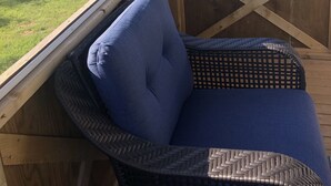 A room with a view of a lake, a wooden deck, and a wicker chair with a cushion. - Bluewaters Retreat Bachelor Unit (Earnscliffe)