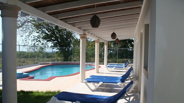 A covered outdoor pool area with lounge chairs and a swimming pool. - Villas Michaela Caribean (Cabarete)