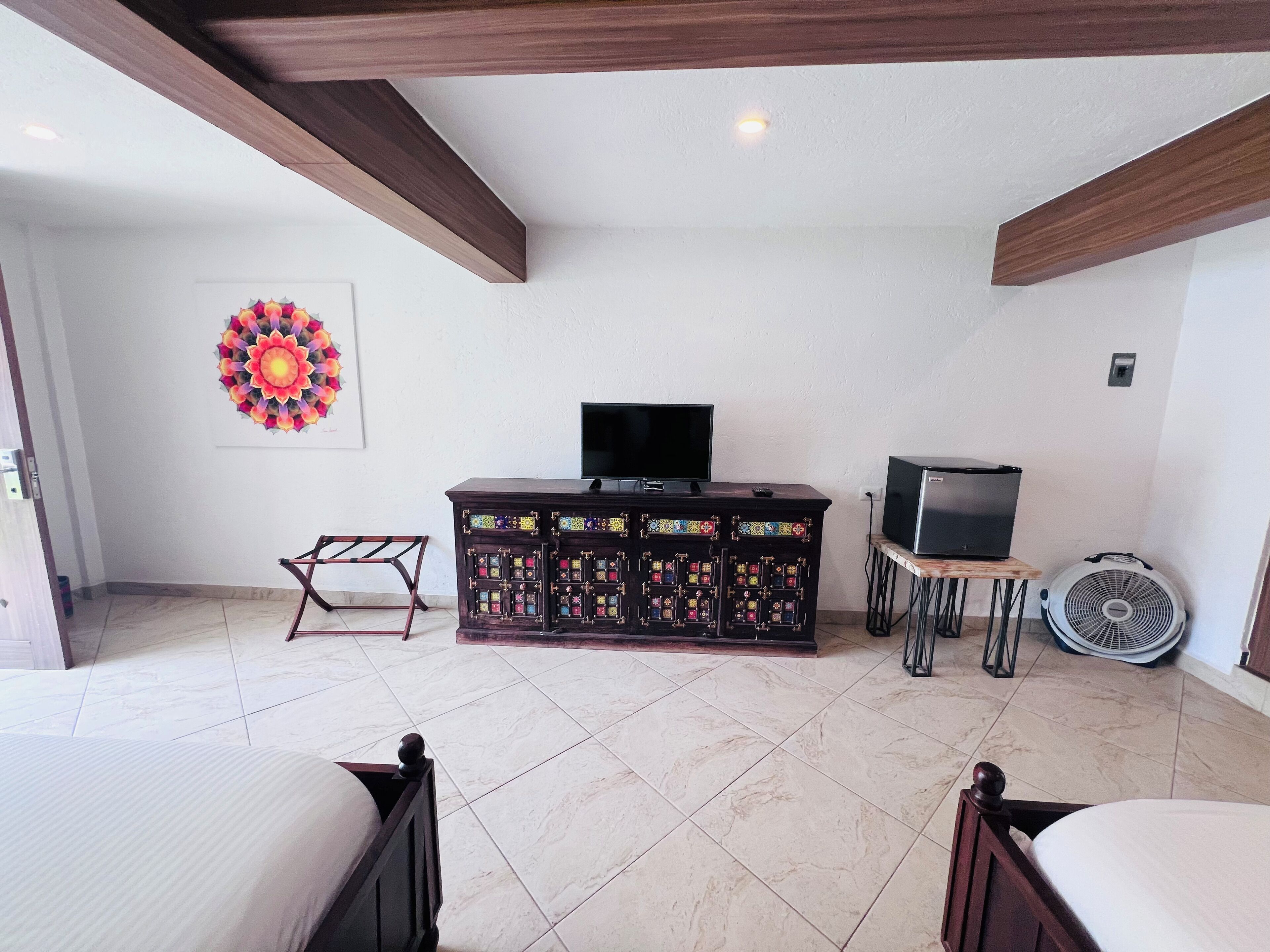 Una habitación con una cama, un televisor sobre un mueble, un armario y un ventilador.