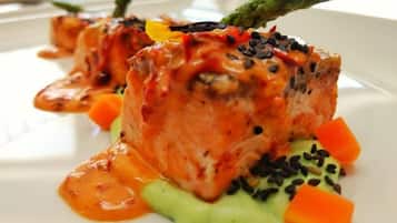 Un plat composé de saumon, de légumes et d’une sauce, le tout servi dans une assiette.