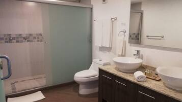 Un baño moderno con ducha, inodoro y dos lavamanos.