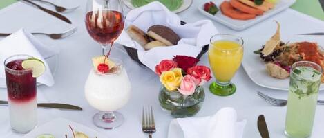Una mesa servida con varios platos, bebidas y un pequeño jarrón de flores.