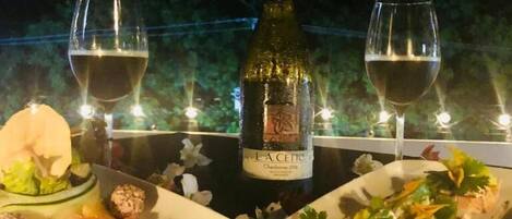 Una mesa con dos platos de comida, una botella de vino y dos copas de vino.