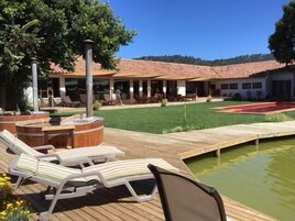 Un área de piscina con sillones de descanso, un jacuzzi y una terraza de madera.