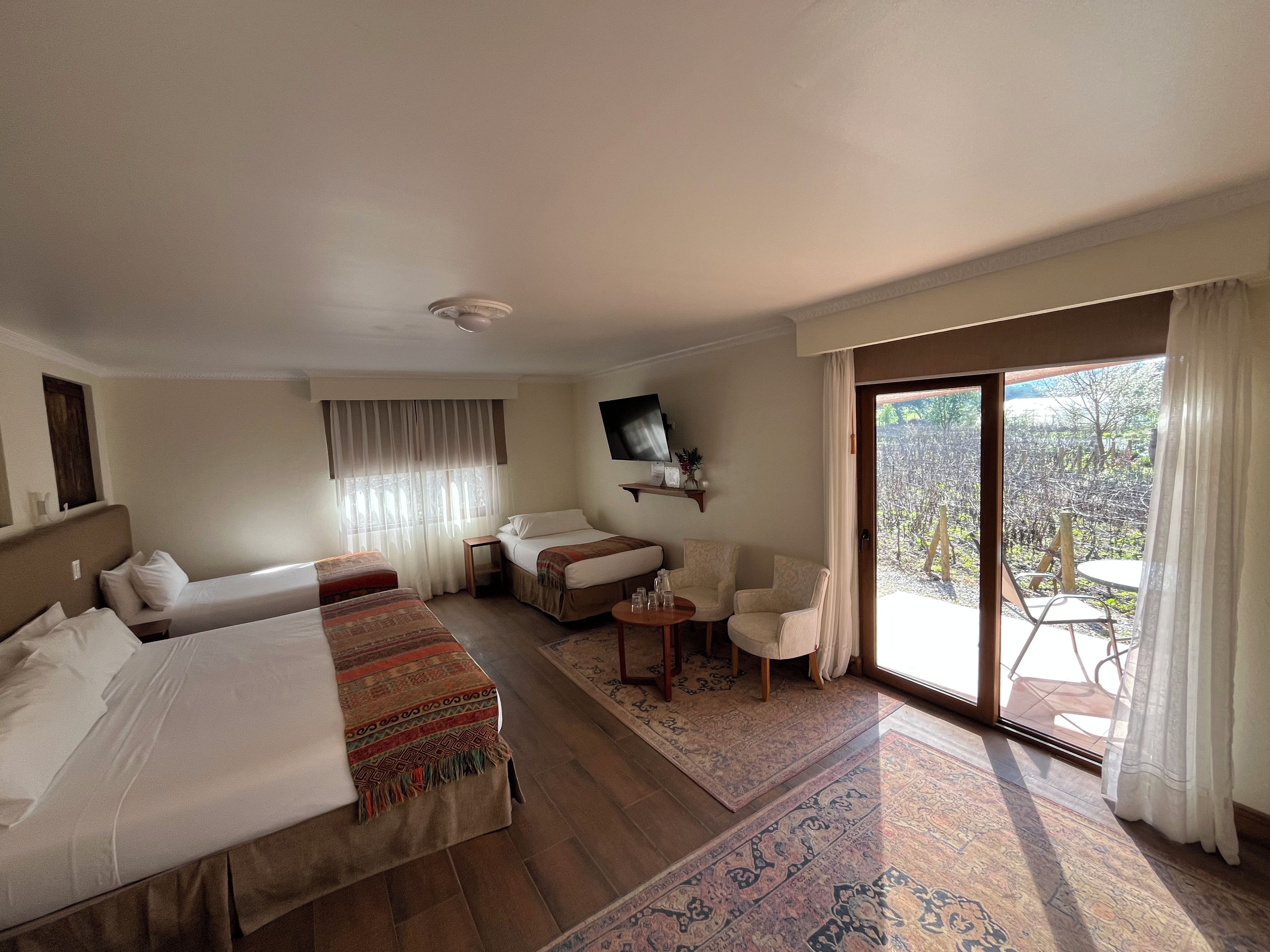 Une chambre d’hôtel avec deux lits, un canapé, une petite table et un téléviseur.
