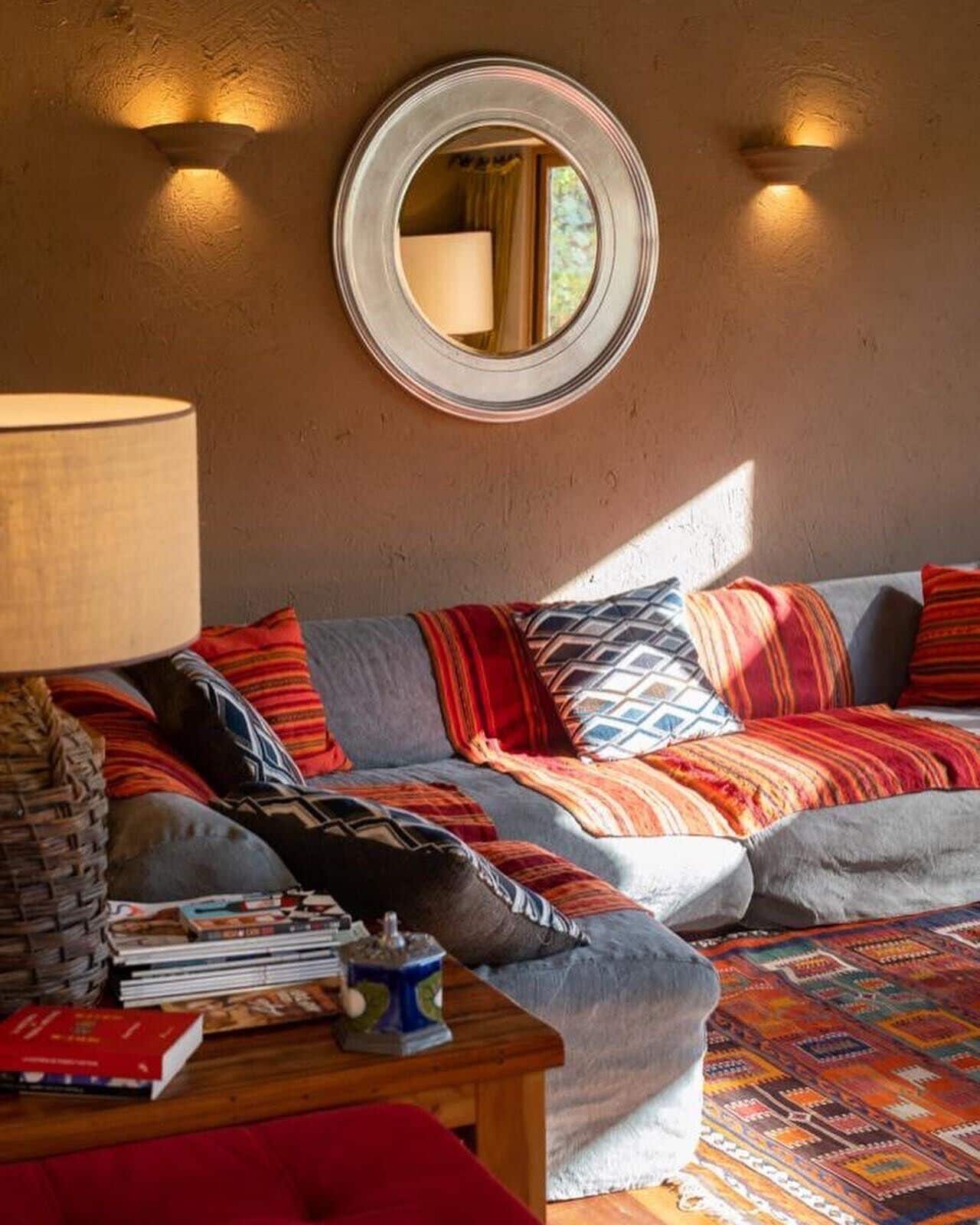 Un salon chaleureux avec un canapé, une table basse et un miroir au mur.