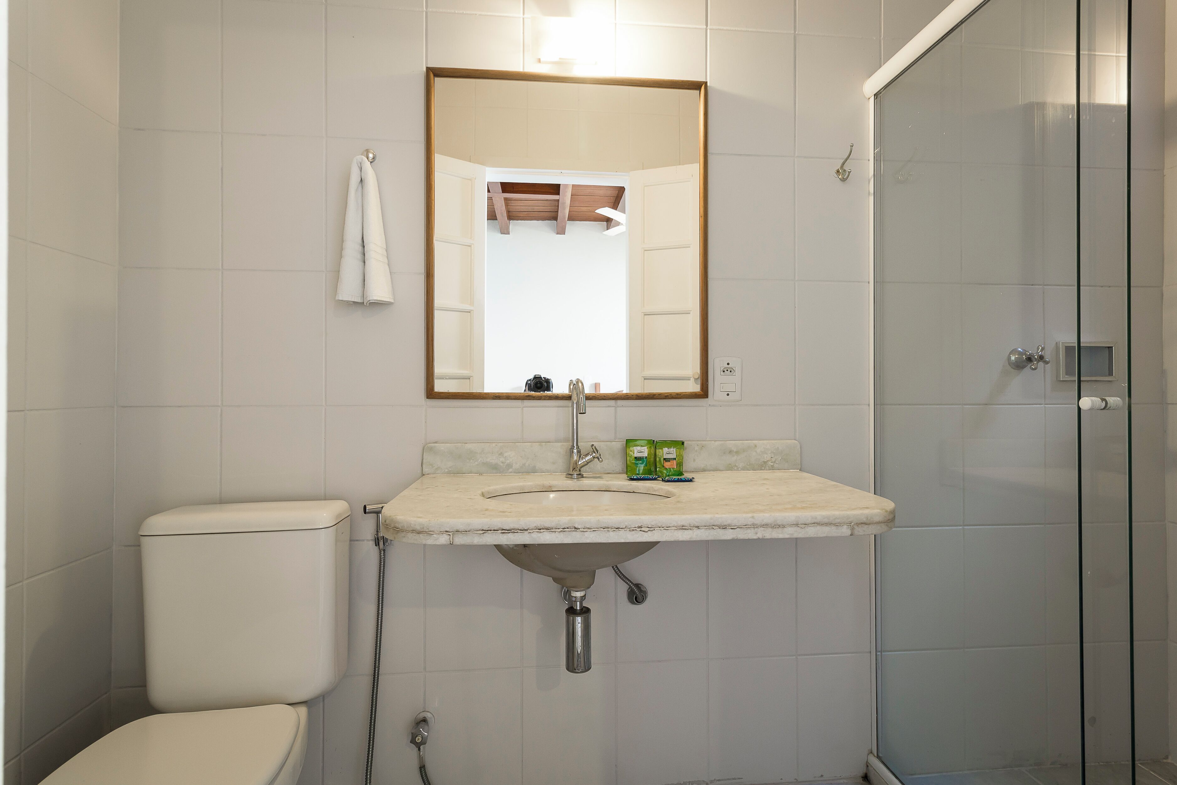 Un baño con inodoro, lavabo, espejo y ducha.