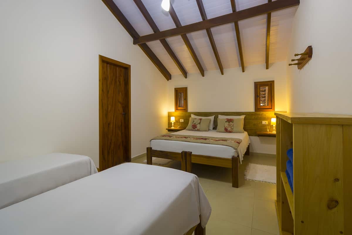 Une chambre à coucher avec un lit en bois, deux tables de chevet avec des lampes, une armoire en bois et une porte.