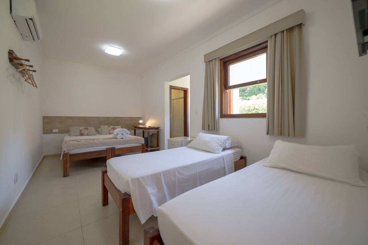 Une chambre d’hôtel avec deux lits simples, une petite table de chevet, une commode, un miroir et une fenêtre avec des rideaux.