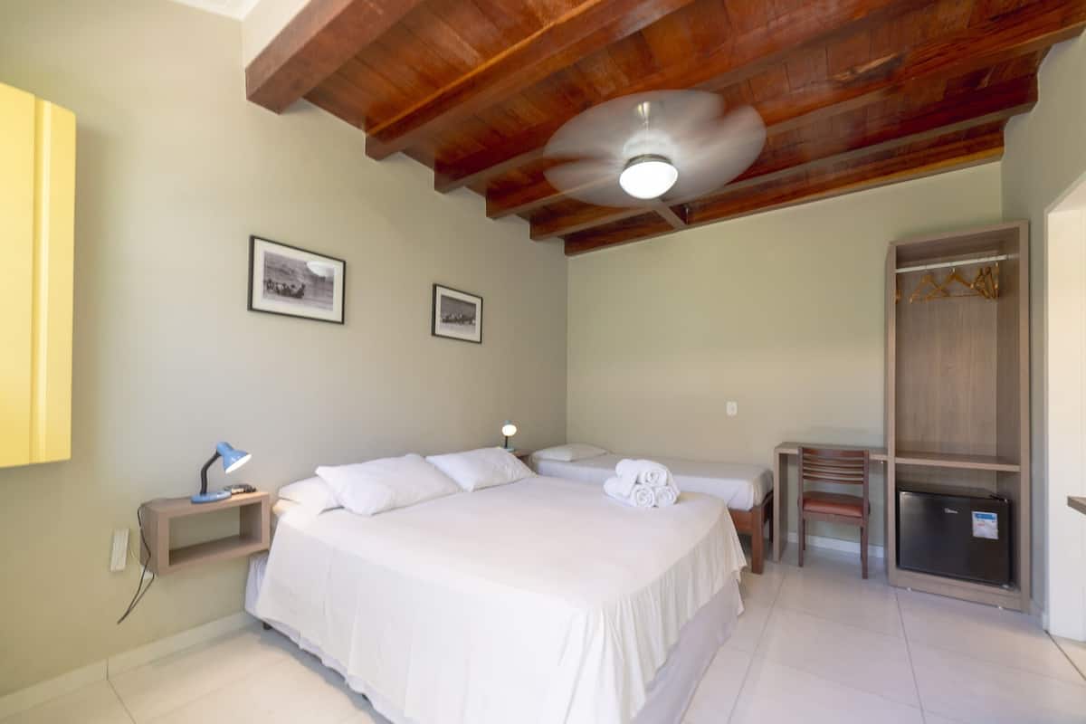 Une chambre à coucher avec un grand lit, un bureau, une chaise, une armoire et un ventilateur de plafond.