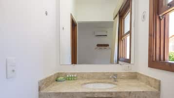 Un baño con lavamanos, espejo y ventana.
