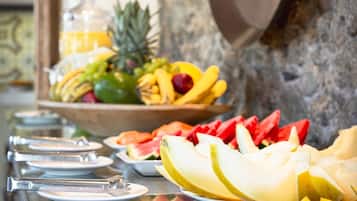 Un buffet garni de différents fruits, avec un saladier rempli de fruits en arrière-plan.