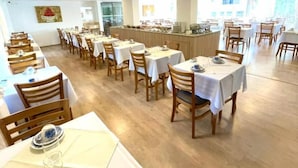 A spacious dining area with multiple tables and chairs, a central bar area, and large windows allowing natural light. - Pousada Itália Moderna (Campos do Jordão)