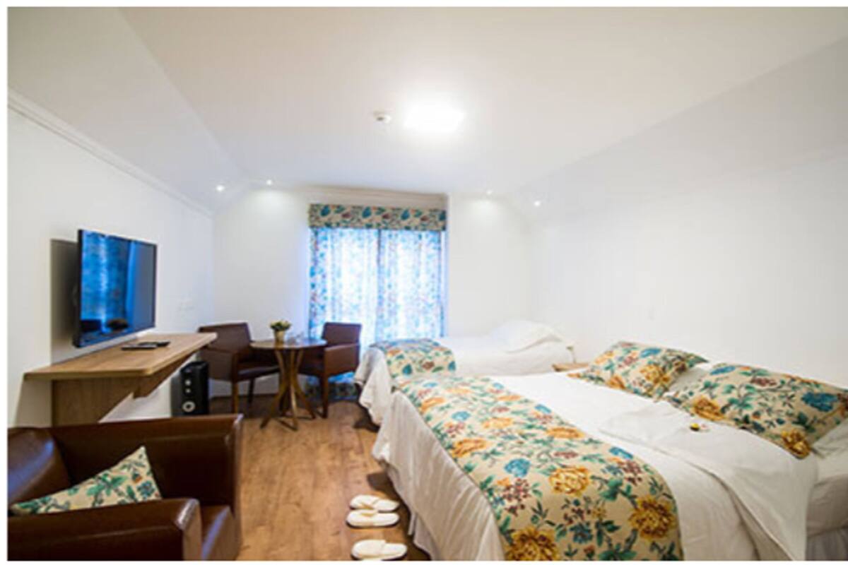 A hotel room with a bed, a desk, a chair, and a television.