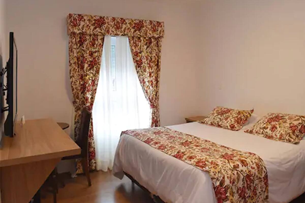 A bedroom with a bed, a desk, and a chair.