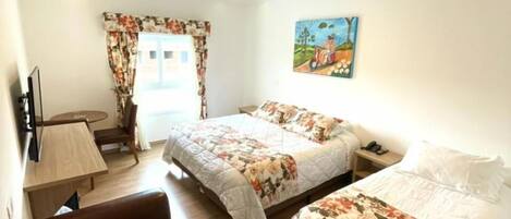 A hotel room with two beds, a sofa, a desk, and a painting on the wall.