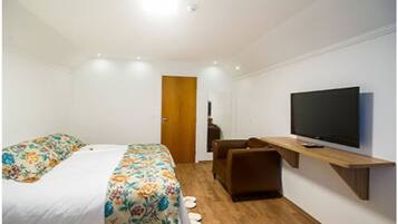 Una habitación de hotel moderna con una cama, televisión, escritorio y una silla.