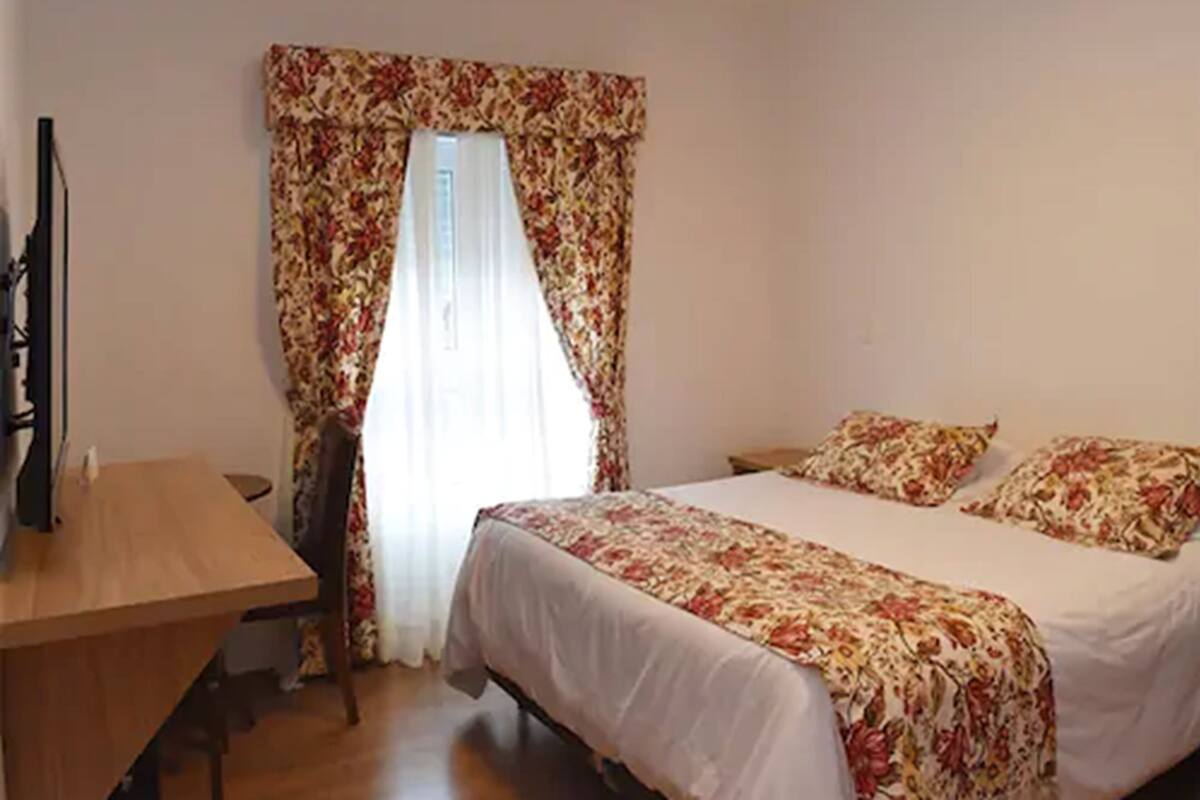 A bedroom with a bed, a desk, and a chair.