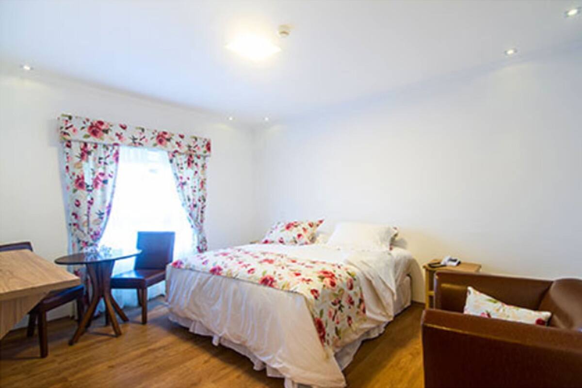 A bedroom with a bed, a desk, a chair, and a sofa.