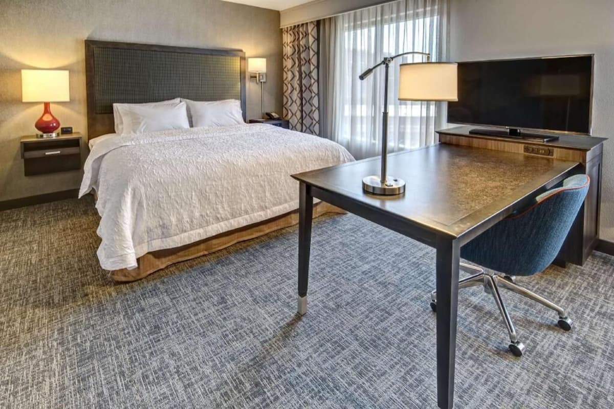 Une chambre d’hôtel équipée d’un lit, d’un bureau, d’une chaise, d’une télévision, d’une lampe et d’une table de chevet.