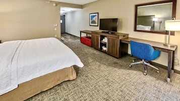 A hotel room with a bed, a desk with a computer, a TV, and a mirror.