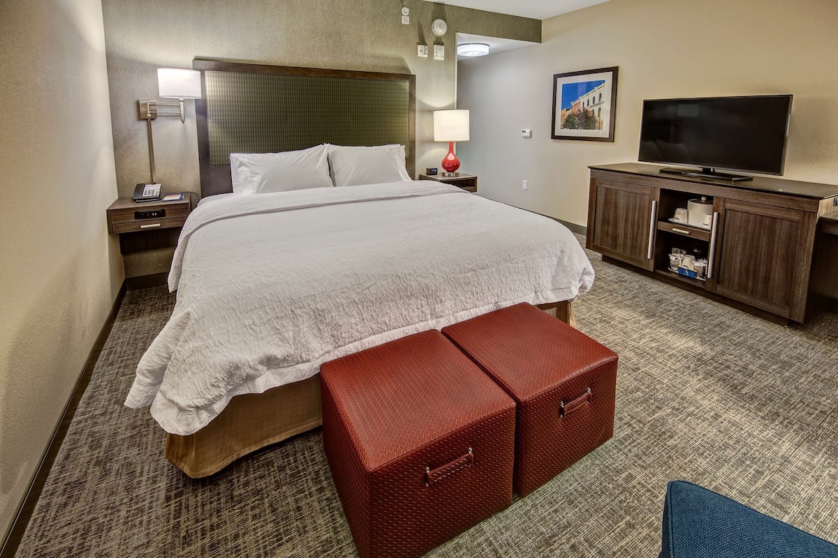 Une chambre d’hôtel avec un grand lit, une télévision, un bureau et un meuble de rangement rouge.